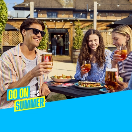 A graphic banner promoting Summer at Flaming Grill venues, the image shows a group of friends sat round a table in a Flaming Grill venue with served food and drinks with text saying 'Go on it's Summer.'