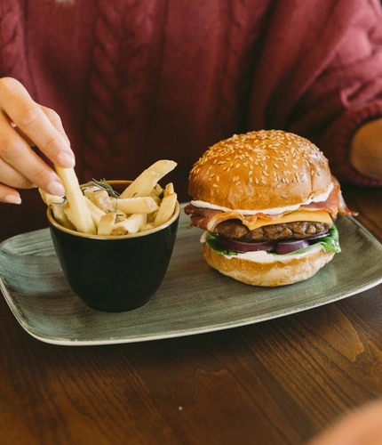 Bacon cheeseburger in a sesame-seed bun with lettuce, red onion and mayonnaise, served with rosemary-topped chips and Old Mout cider.
