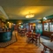 The ground floor bar and interior restaurant seating area at The Globe; with checkerboard tiles in front of the counter, TVs on the walls, two gaming machines, and bar stool seating.