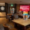 The interior restaurant seating area with tables, chairs, exposed brick wall with TV screen and dartboard in the background at The Castle View.