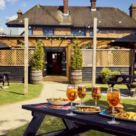 A image of a bench with served food and drinks in a Flaming Grill beer garden.