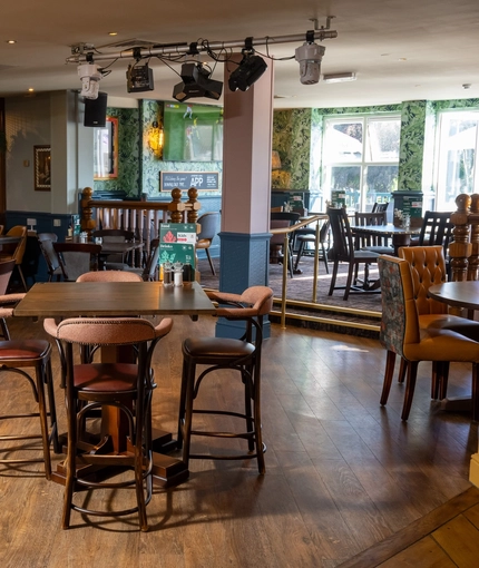 The interior restaurant seating area of the Rudds Arms; with TVs on the walls, and stage lights hanging on the ceiling.