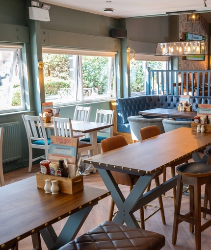 The interior restaurant seating area at The Man On The Moon, with upholstered seating, wooden tables and a TV on the walls.