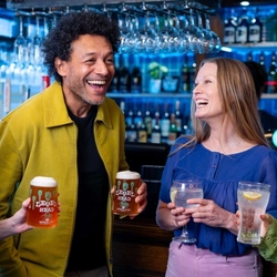 A group of people by the bar enjoying drinks.