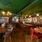 The bar and interior restaurant seating area at the King's Head, with dark wood floors; green, textured wallpaper on the ceiling; and a long, red, upholstered booth seat along one wall by the window.