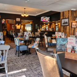 The interior restaurant seating area and bar at The Carousel, with upholstered seats and a TV on the wall.