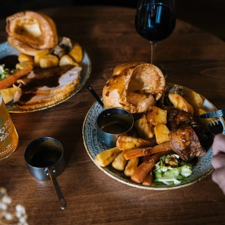 A close up image showing 2 people sat at a table within the interior restaurant seating area enjoying drinks and a roast at a Heritage venue.