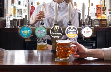 A hand holding a pint on a bar.