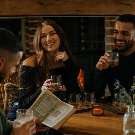 An image of 3 customers enjoying a Burns Night Whiskey flight board sat at a table within the interior restaurant seating area of The Crown.