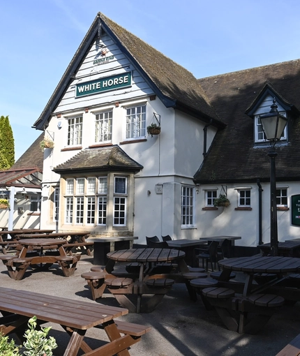 Exterior facade and beer garden of a pub with a dining area.