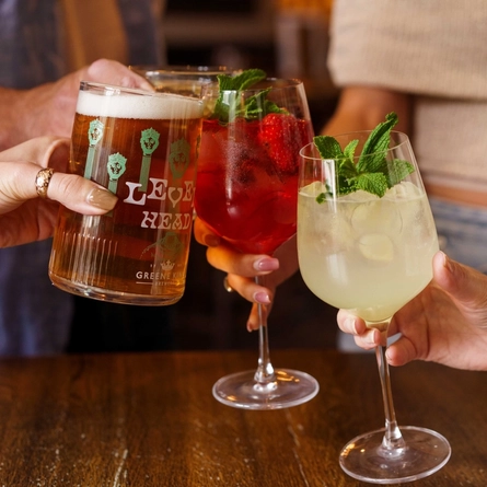 People at an indoor table holding a variety of cocktails and Level Head.