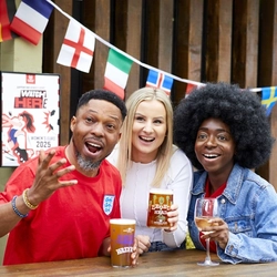 A mixed group of people, sitting at an outdoor table, reacting to a sport event.
