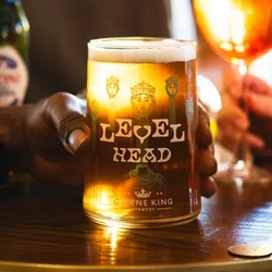 People holding drinks at a table. A glass of Level head is in focus.