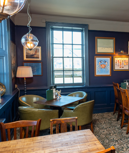 An image of the interior restaurant seating area with tables, chairs, cushioned seating and hanging pendant lighting at The Spice Island.