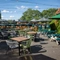 The exterior beer garden seating area at the Rudds Arms in Marton-In-Cleveland; with shade umbrellas on some of the tables, and string lights overhead.