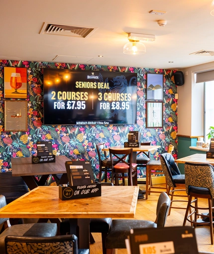 The interior restaurant seating area at the Counting House, with brightly coloured wallpaper, and a TV on the wall.