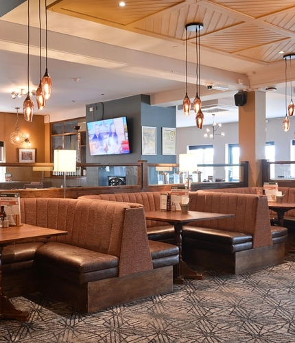 Interior dining area of a pub with a TV and a fireplace.
