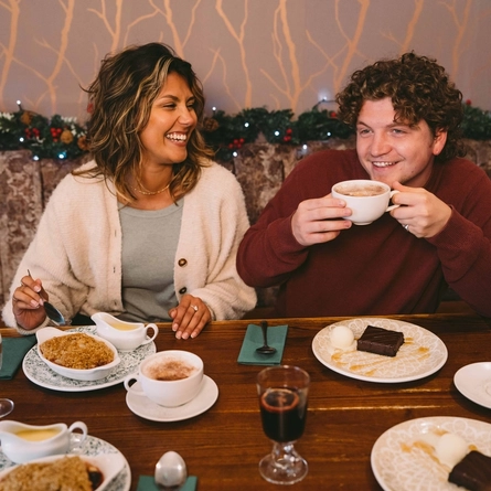 A group of people seated at a festive decorated table  with plated meals and drinks in front of them.