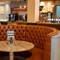 A circular restaurant booth seat surrounding a small wooden table, in the bar area of The Weathervane.