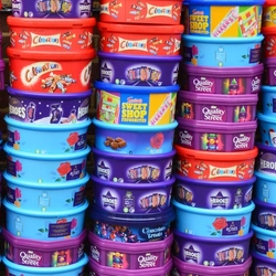 Three piles of plastic sweet and chocolate tubs.