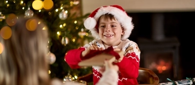 An image of an adult and child exchanging a gift while enjoying fruit juice and dishes from the Breakfast with Santa menu at Chef & Brewer venues.