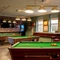The interior gaming area at the Wooden Bridge in Guildford, with pool tables, TVs on the walls, a gaming machine, and seating areas.