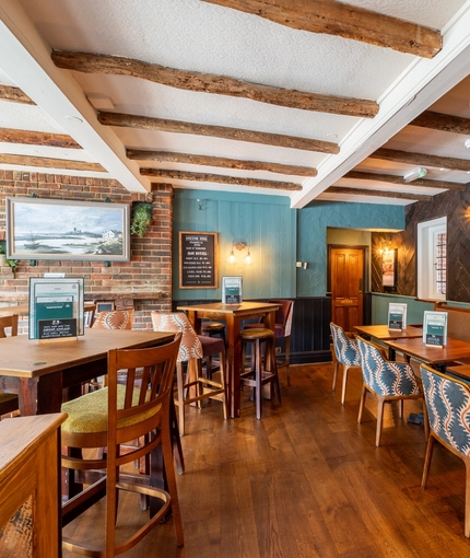 An interior restaurant seating area at The Walkford, with an upholstered booth seat along one wall, and wooden beams on the ceiling.