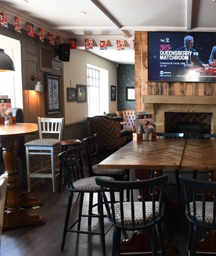 Interior dining area of a pub with a TV and a fireplace.