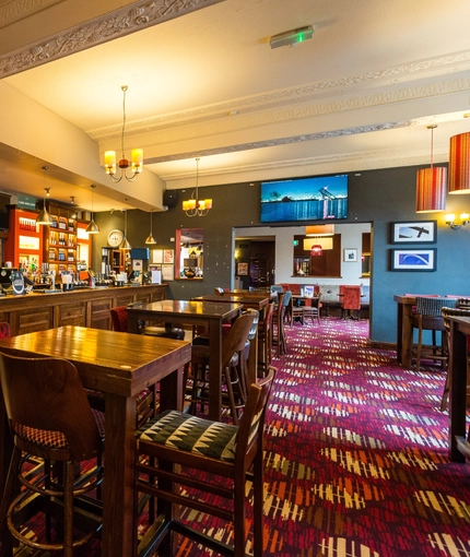 Interior dining area of a pub with a bar and a TV.