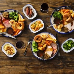 An overhead image of several plated roast dinners on an indoor table.