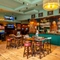 The bar and interior restaurant seating area at the Phoenix, with wood panelled walls, a gaming machine, and TVs on the walls.