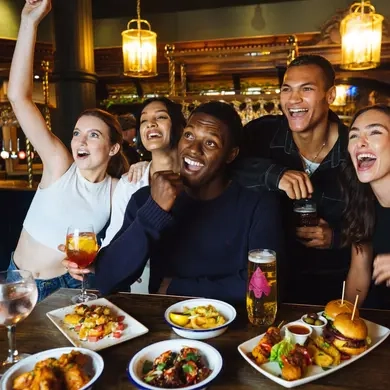 Friends cheering in the pub whilst eating and drinking