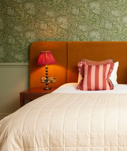 Hotel double bed with scatter cushions and bedside tables either side with lamps on top