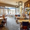 The interior restaurant seating area of The Flying Horse in Heald Green, featuring wooden tables, upholstered chairs and artwork on the walls.