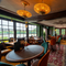 The interior restaurant seating area at The London Apprentice, with wooden flooring, two jewelled ceiling lights, windows overlooking the River Thames, a fireplace, and decorative plaster on the ceiling.