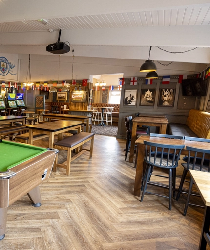 Interior dining area of a pub with a pool table and a TV.