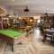 Interior dining area of a pub with a pool table and a TV.