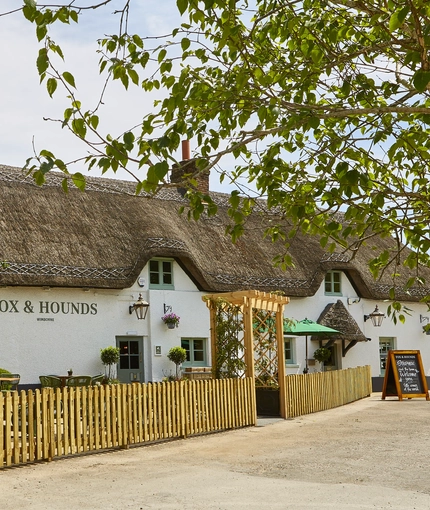 The exterior facade and beer garden seating area of The Fox & Hounds in Wimborne.