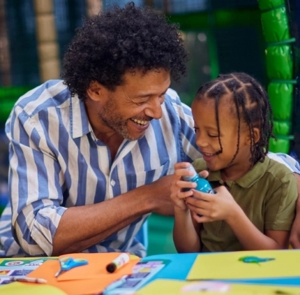 An image of a child and a man participating in crafts at a Wacky Warehouse.
