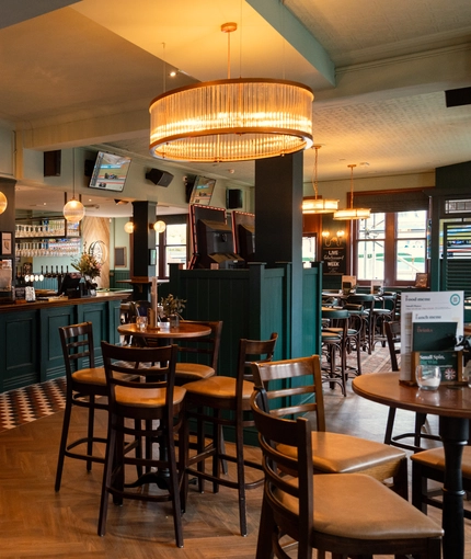 The bar and interior restaurant seating area at The Richmond Arms, with TVs on the wall, and gaming machines.