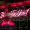 A close up view of a neon pink sign spelling "The Talbot" in cursive lettering; on a wall inside The Talbot.