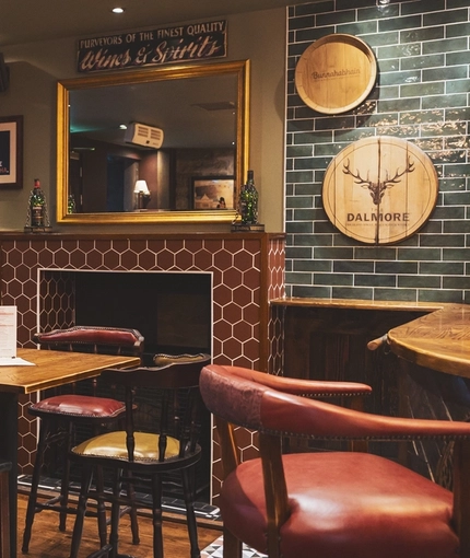 The interior restaurant seating area at the Albanach in Edinburgh with an upholstered booth corner seat and a fireplace.