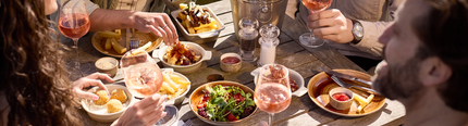 An image of 4 friends sat at a table within the exterior beer garden enjoying glasses of rose wine and a selection of picky bits at a Chef & Brewer venue.