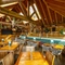 The exterior under cover seating area at The Walkford, with string lights and flowers hanging from the vaulted ceiling, potted plants and chalkboards on the wooden walls, and padded bench seats along one wall.