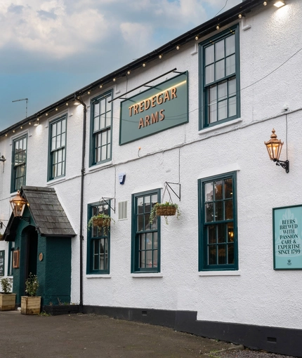 The exterior facade and signage of the Tredegar Arms in Bassaleg, with flower baskets hanging on the wall.