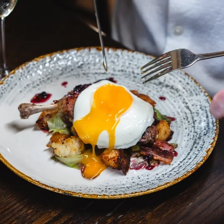 main meal with egg on display with a side of fries plated on table with a glass of fizz