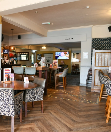 Interior dining area of a pub with a bar and a TV.