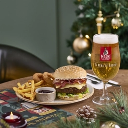 An advertising image showing a burger dish and pint of beer from the Festive Spread menu sat on a table within the interior restaurant seating area at a Chef & Brewer venue.