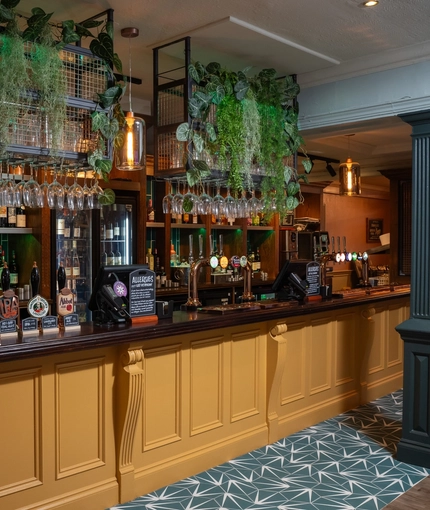 The bar inside The Grosvenor, with wine glasses hanging in racks above the counter.