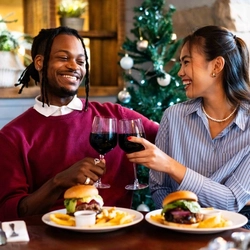 a man and a woman sitting at a table with a plate of food